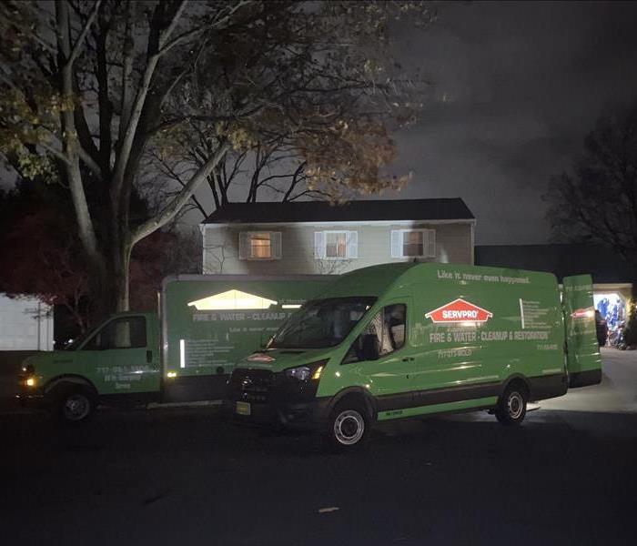 Two SERVPRO vehicles parked in front of a house fire