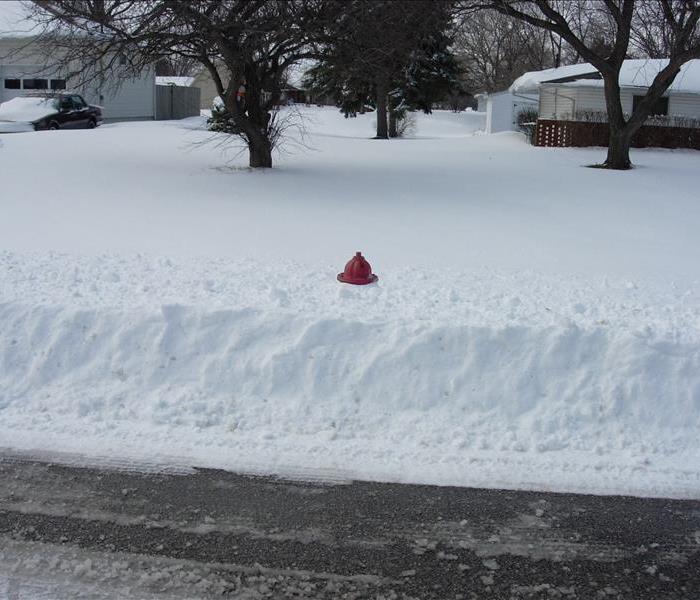 snow covering all but the top of a fire hydrant outside of a home