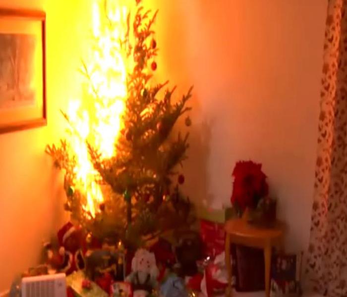 Christmas tree on fire in corner of house